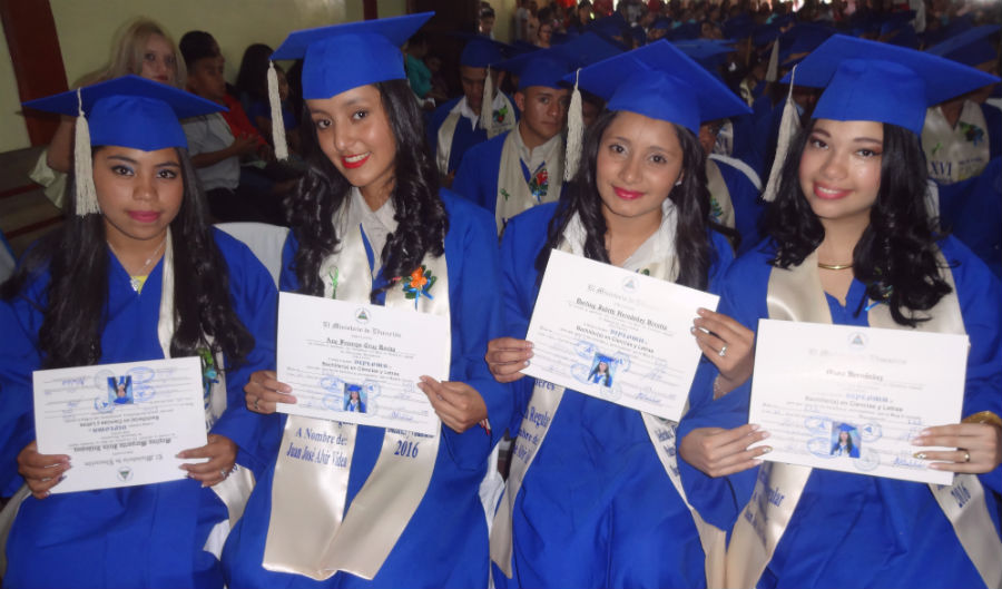 four senior girls hold their diplomas at graduation